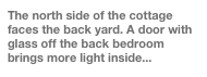 The north side of the cottage faces the back yard. A door with glass off the back bedroom brings more light inside...